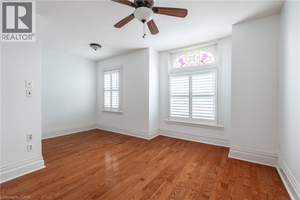 This room features polished hardwood flooring, white walls, and a ceiling fan - 198 Bay Street N, Hamilton, ON - Indoor Photo Showing Other Room