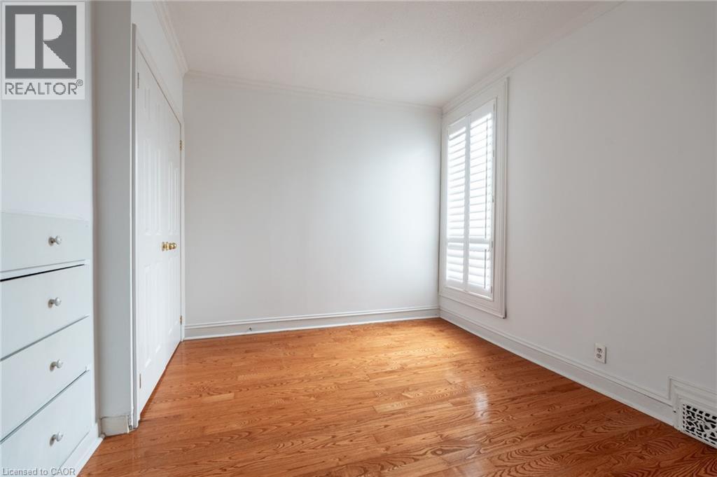 This room features polished hardwood flooring, white walls, and a window with white louvered shutters - 198 Bay Street N, Hamilton, ON - Indoor Photo Showing Other Room