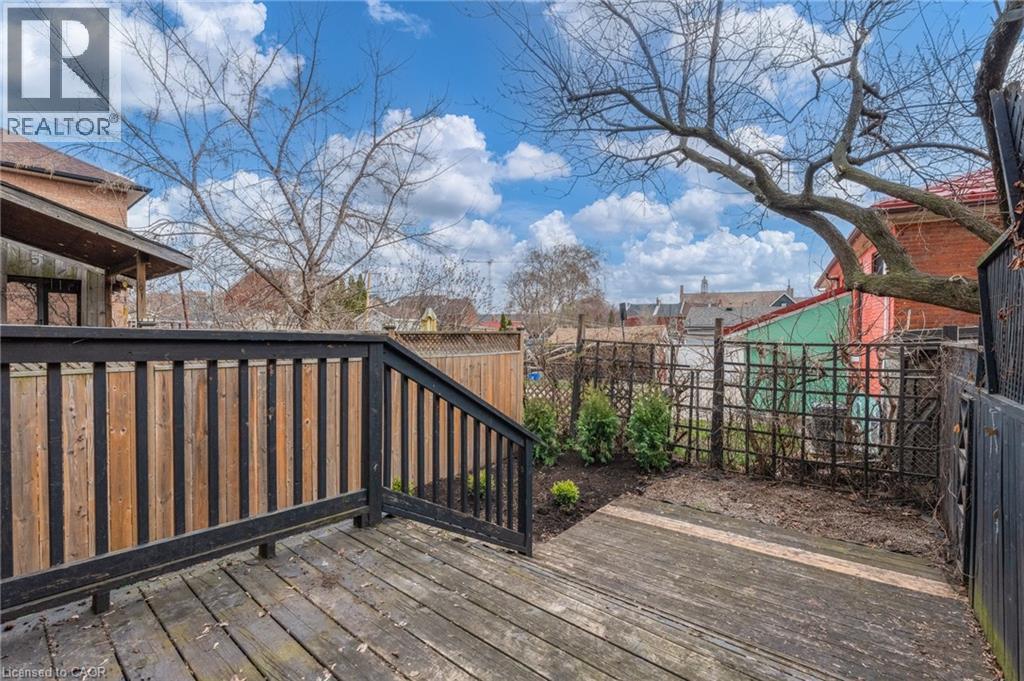 The property features a wood deck with a dark-stained railing, offering views of the yard - 198 Bay Street N, Hamilton, ON - Outdoor