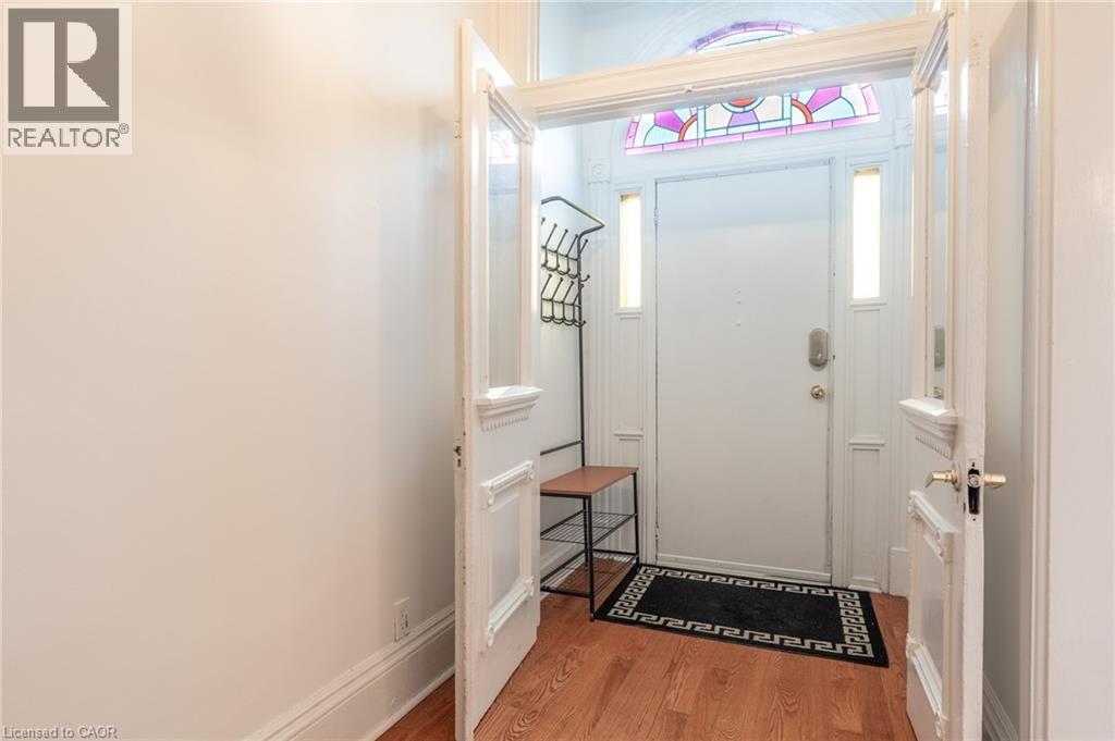 Foyer featuring a decorative stained glass transom window, a white entry door with side lights, and hardwood flooring - 198 Bay Street N, Hamilton, ON - Indoor Photo Showing Other Room