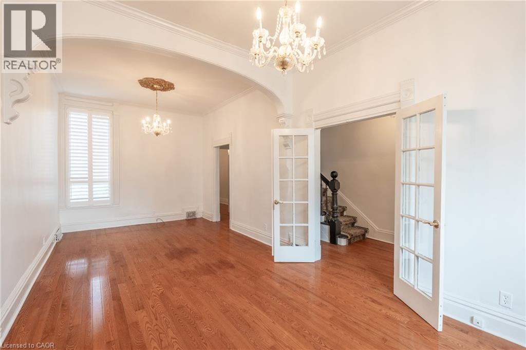 This room features hardwood floors, white walls, and an arched entryway - 198 Bay Street N, Hamilton, ON - Indoor Photo Showing Other Room
