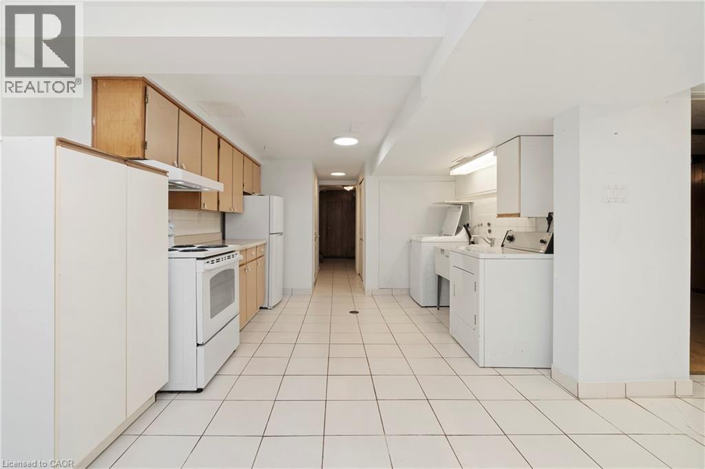The property features a kitchen and utility area with white tile flooring - 36 Buckingham Drive, Hamilton, ON - Indoor