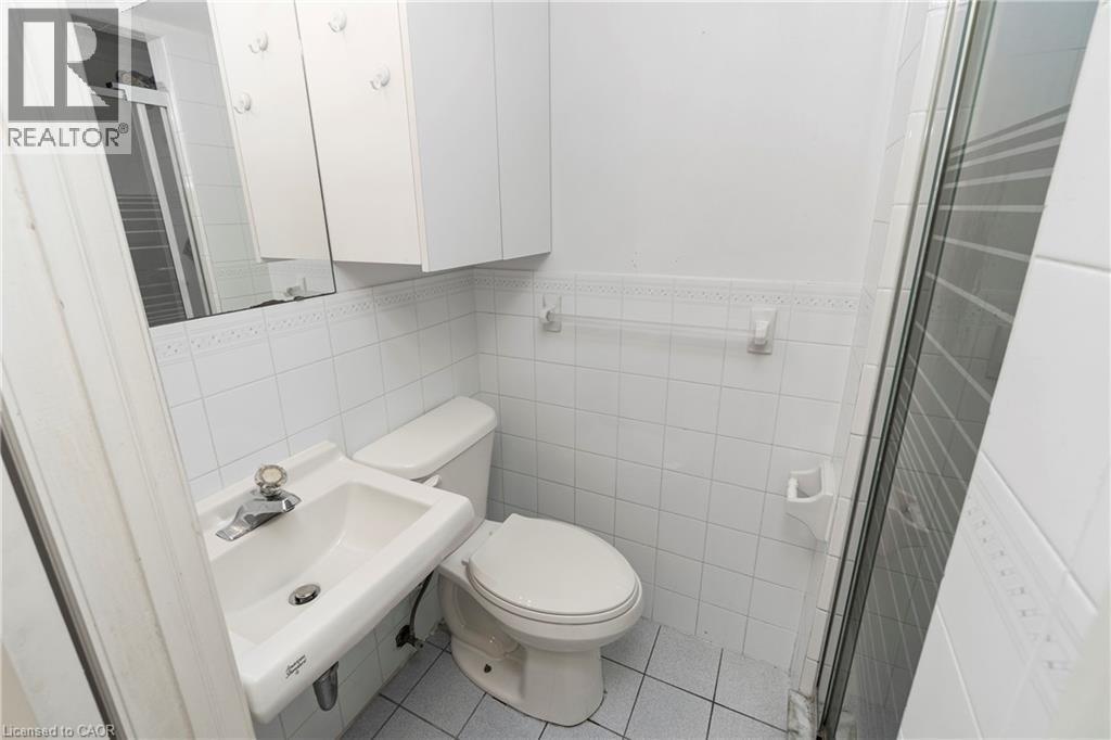 Bathroom with a white toilet, wall-mounted sink, and a shower enclosure with a glass door - 36 Buckingham Drive, Hamilton, ON - Indoor Photo Showing Bathroom