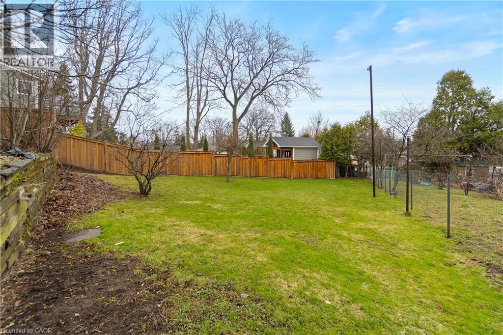 This property features a spacious yard with a lush green lawn and a wooden privacy fence - 36 Buckingham Drive, Hamilton, ON - Outdoor