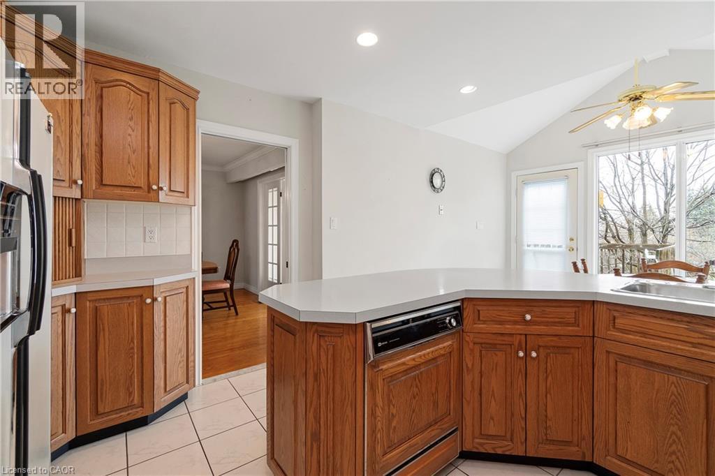 The kitchen features wood cabinetry, light-colored countertops, and tiled flooring - 36 Buckingham Drive, Hamilton, ON - Indoor Photo Showing Kitchen