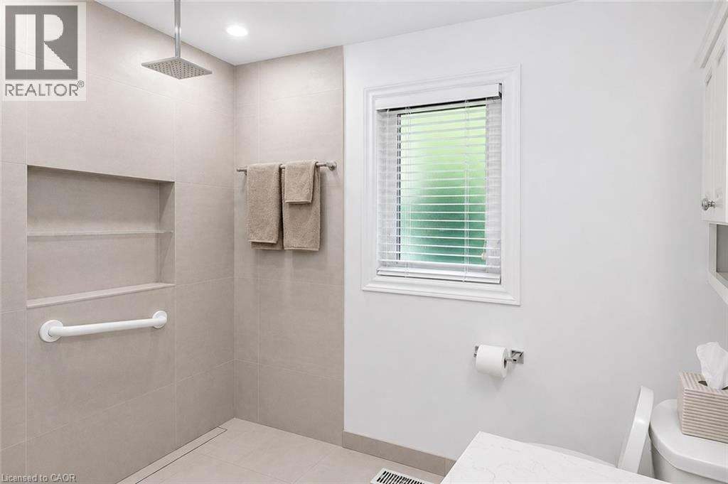 Tiled shower enclosure featuring a square rainfall shower head and built-in shelving - 23 Percy Court, Hamilton, ON - Indoor Photo Showing Bathroom