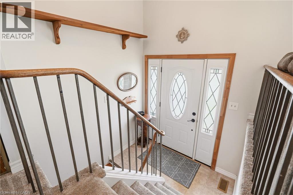 Inviting entryway featuring a white door with decorative glass inserts and light wood trim, complemented by a carpeted staircase with a wood handrail and metal spindles - 2349 Middlesmoor Crescent, Burlington, ON - Indoor Photo Showing Other Room