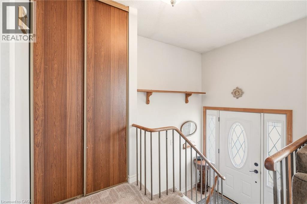 Entryway featuring a white door with decorative glass inserts, a wood-framed mirror, and a wooden railing - 2349 Middlesmoor Crescent, Burlington, ON - Indoor Photo Showing Other Room