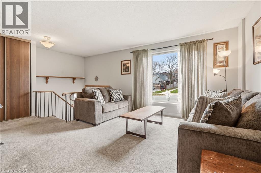 Living area with light-colored carpet, a large window, and a wood-paneled wall with sliding doors - 2349 Middlesmoor Crescent, Burlington, ON - Indoor Photo Showing Living Room