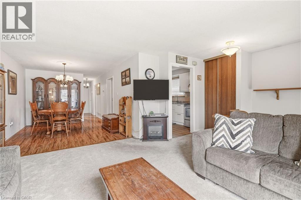 Living area featuring light colored carpeting, with a distinct dining area boasting wood flooring - 2349 Middlesmoor Crescent, Burlington, ON - Indoor Photo Showing Living Room
