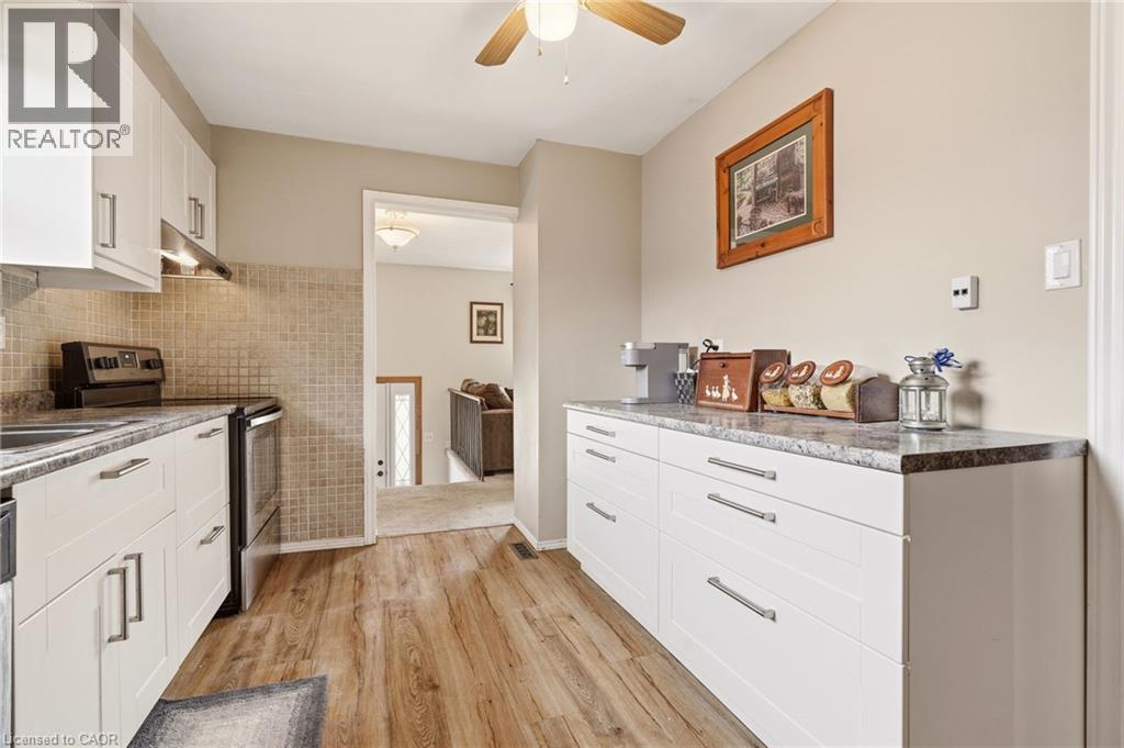 The kitchen features white cabinetry, a tiled backsplash, and wood-look flooring - 2349 Middlesmoor Crescent, Burlington, ON - Indoor Photo Showing Kitchen