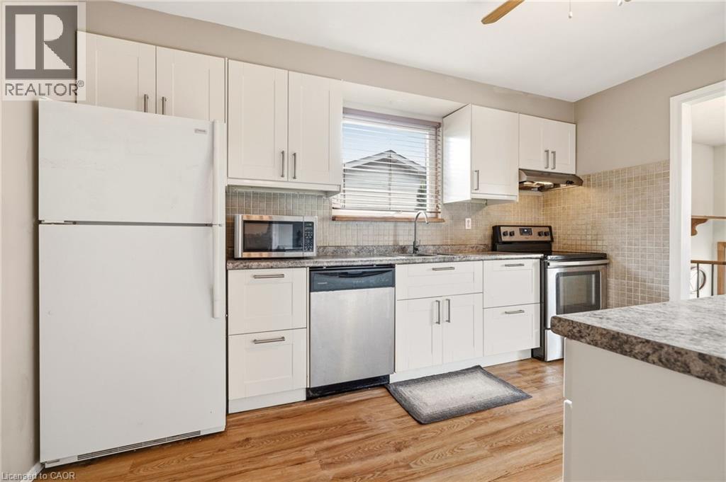 This kitchen features white cabinetry, a tiled backsplash, and a window with blinds - 2349 Middlesmoor Crescent, Burlington, ON - Indoor Photo Showing Kitchen