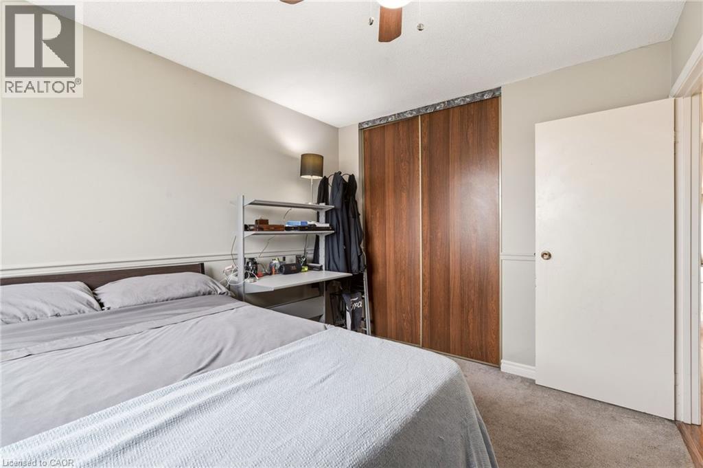 This room features soft gray carpet flooring, a ceiling fan, and a large closet with wooden sliding doors - 2349 Middlesmoor Crescent, Burlington, ON - Indoor Photo Showing Bedroom