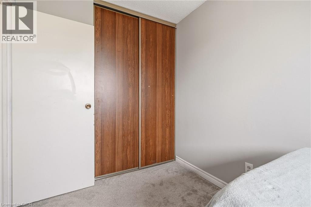 This room features light grey walls and light grey carpeting, with a white door and a closet with wood-look sliding doors - 2349 Middlesmoor Crescent, Burlington, ON - Indoor