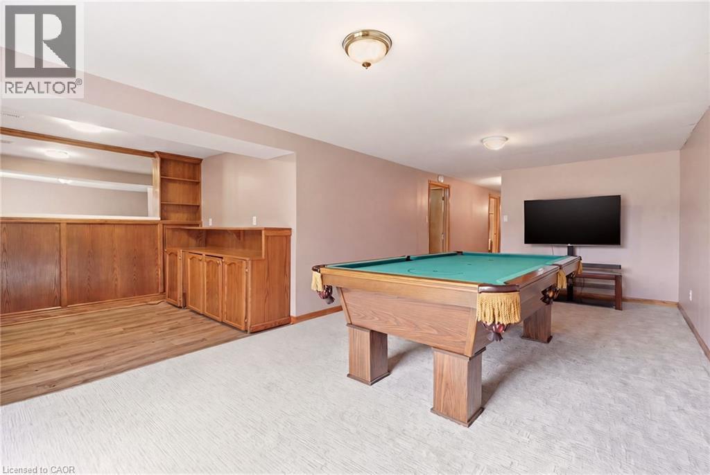 The property features an entertainment area with a pool table, light-colored carpeting, and a built-in bar area with wood paneling and shelving - 2349 Middlesmoor Crescent, Burlington, ON - Indoor Photo Showing Other Room