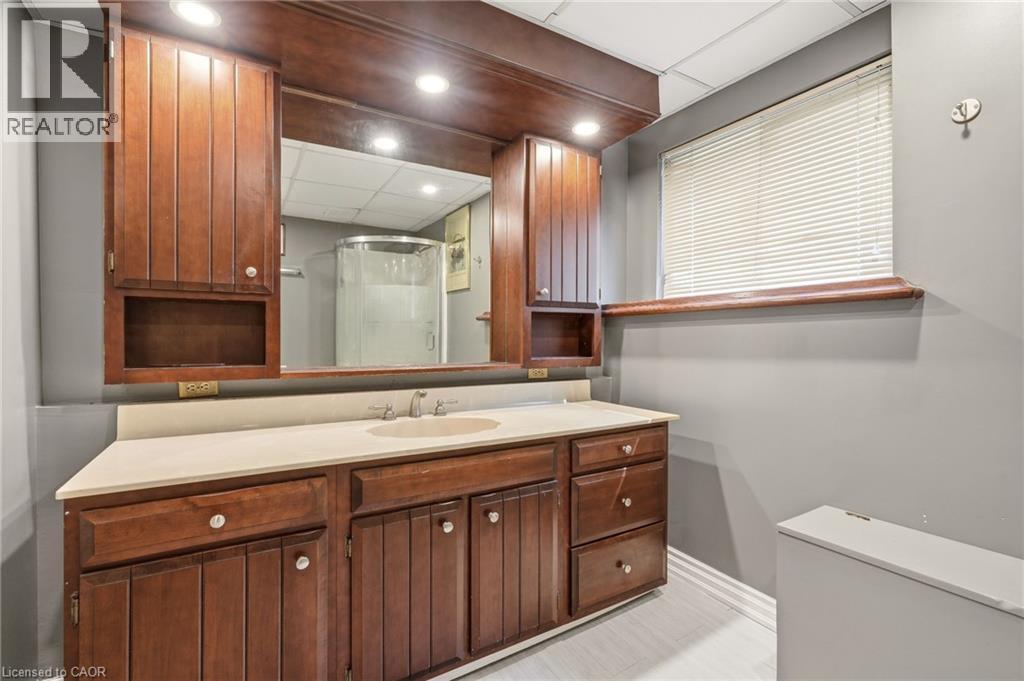 Bathroom vanity with a light-colored countertop, an integrated sink, and dark wood cabinetry with chrome fixtures - 2349 Middlesmoor Crescent, Burlington, ON - Indoor Photo Showing Bathroom