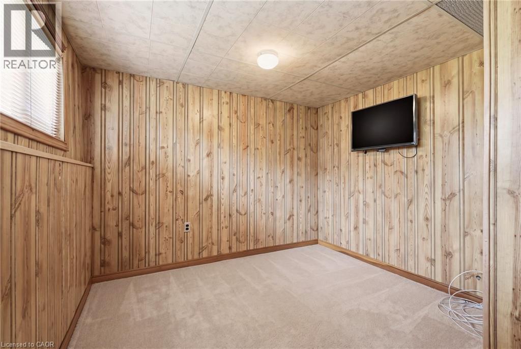 This room features carpeted flooring, wood paneling on the walls, and a window with blinds providing natural light - 2349 Middlesmoor Crescent, Burlington, ON - Indoor Photo Showing Other Room