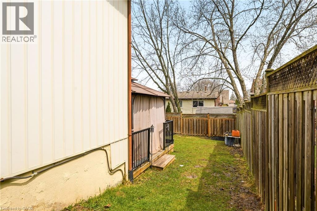The property features a fenced yard with a lawn, a wooden deck, and mature trees - 2349 Middlesmoor Crescent, Burlington, ON - Outdoor