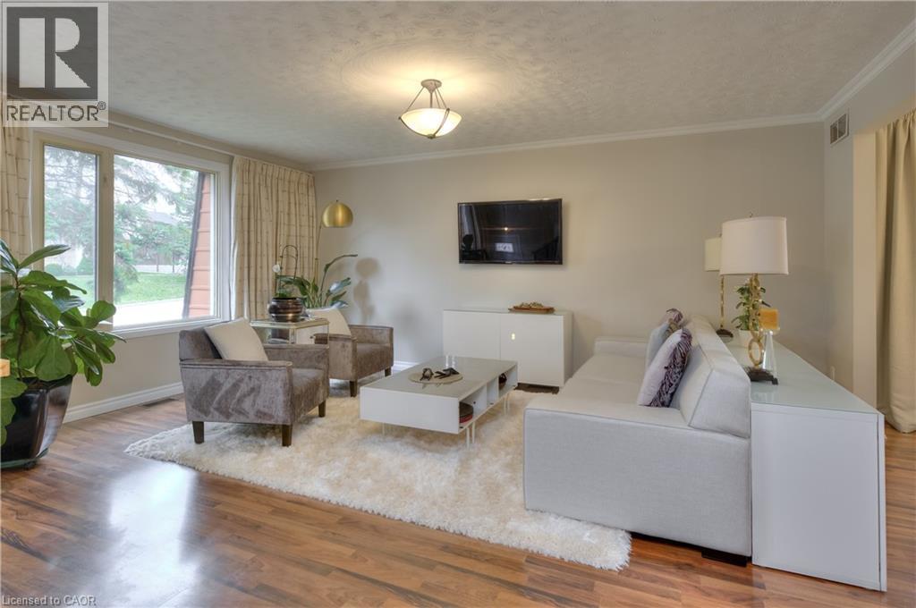 This bright living space features hardwood flooring, a large window providing natural light, and a ceiling light fixture - 42 Culpepper Drive, Waterloo, ON - Indoor Photo Showing Living Room