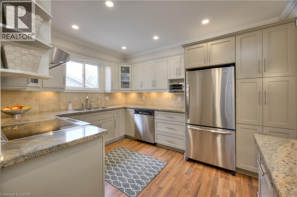 The kitchen features light-colored cabinetry, stainless steel appliances, and granite countertops - 42 Culpepper Drive, Waterloo, ON - Indoor Photo Showing Kitchen With Double Sink
