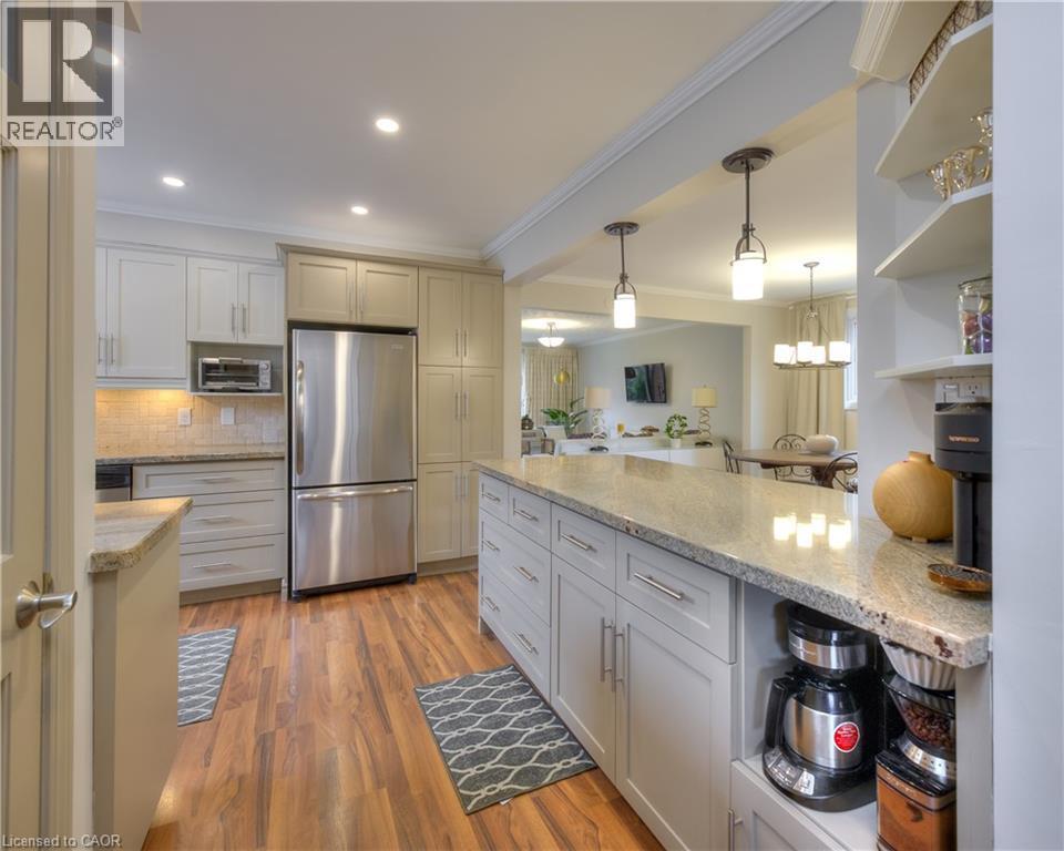 This kitchen features wood flooring, recessed lighting, and a kitchen island with a granite countertop and pendant lighting - 42 Culpepper Drive, Waterloo, ON - Indoor Photo Showing Kitchen With Upgraded Kitchen