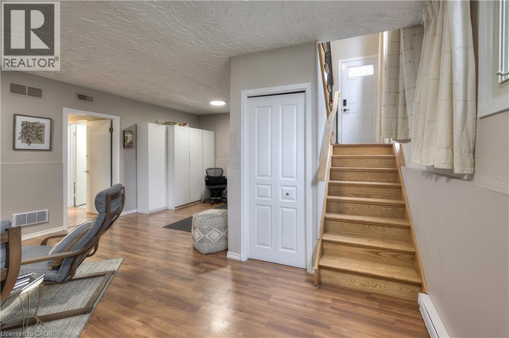 The property features wood-look flooring, a wooden staircase with a wooden handrail, and a white paneled door - 42 Culpepper Drive, Waterloo, ON - Indoor Photo Showing Other Room