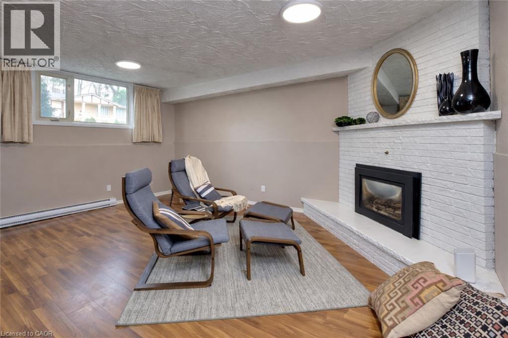Living area featuring hardwood flooring, a white brick fireplace with a mantel, and windows - 42 Culpepper Drive, Waterloo, ON - Indoor With Fireplace
