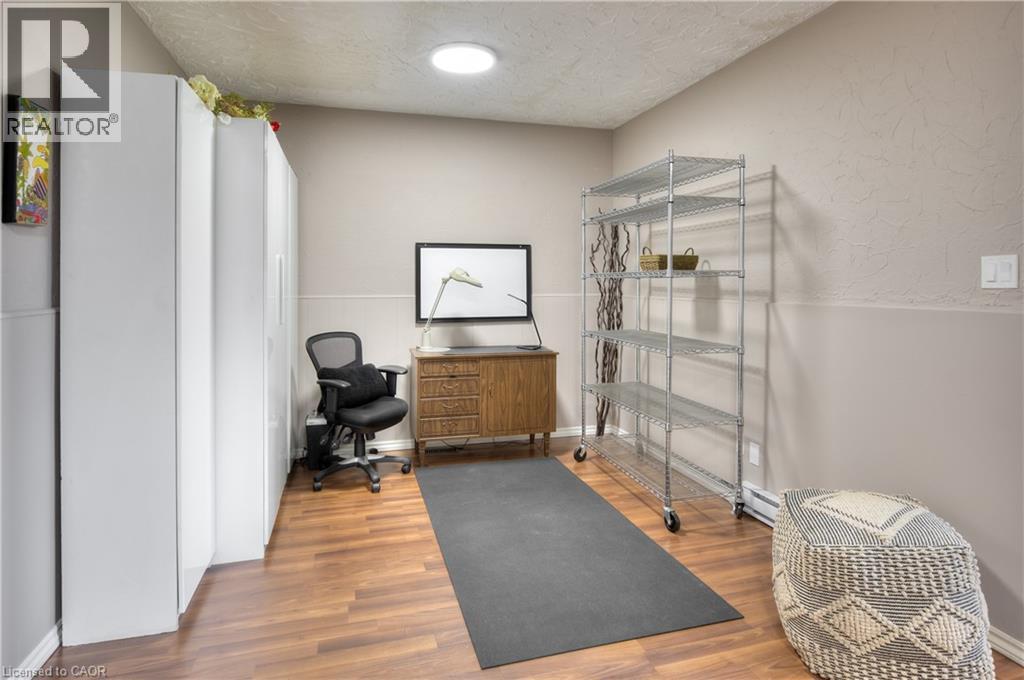 This versatile room features warm-toned flooring, neutral painted walls, and a circular ceiling light fixture - 42 Culpepper Drive, Waterloo, ON - Indoor