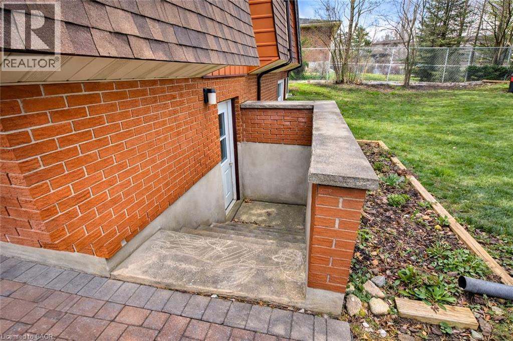 The property features a red brick exterior, a tiered roof, and a concrete staircase leading to a white door - 42 Culpepper Drive, Waterloo, ON - Outdoor
