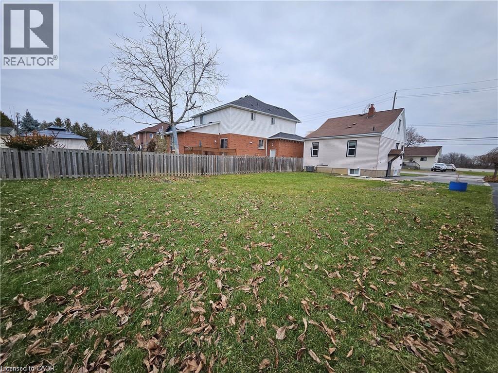 Expansive yard with green grass and a wooden fence along the property line - 1356 Upper Wellington Street, Hamilton, ON - Outdoor With Backyard