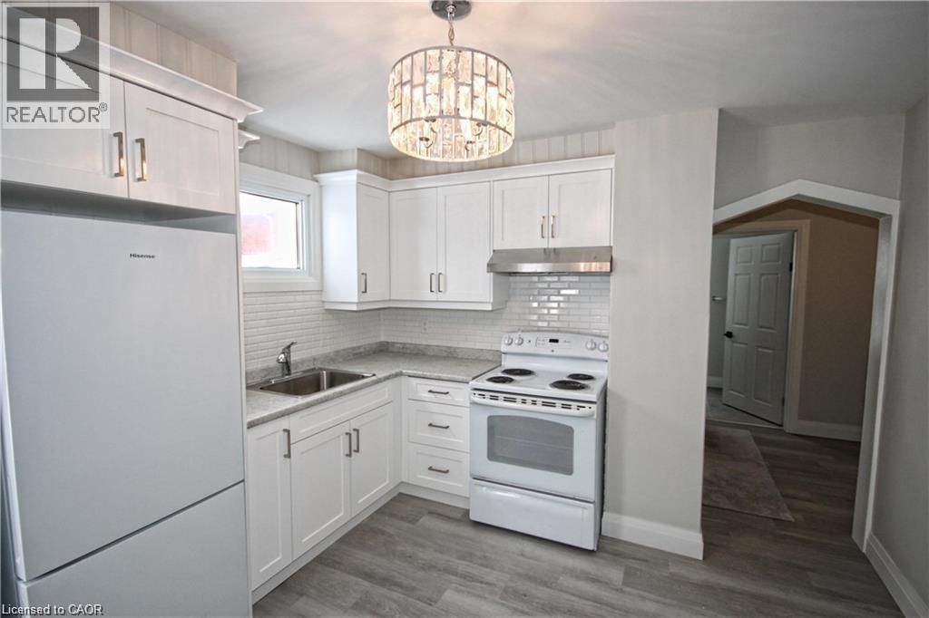 Kitchen featuring white cabinetry, a white stove, a white refrigerator, and a stainless steel sink - 1356 Upper Wellington Street, Hamilton, ON - Indoor Photo Showing Kitchen