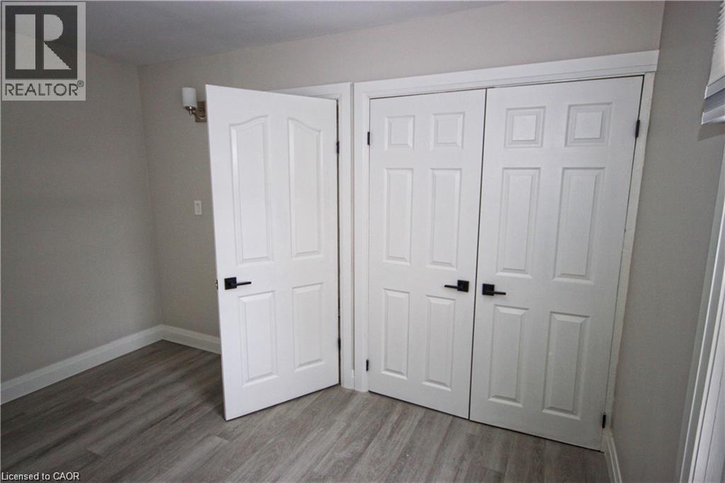 This room features light gray wood-style flooring, light-colored walls, and white trim - 1356 Upper Wellington Street, Hamilton, ON - Indoor Photo Showing Other Room