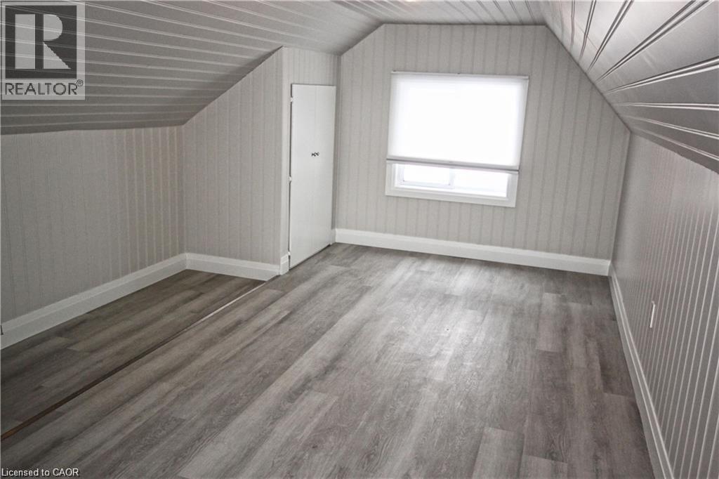 This room features light grey wood-look flooring, a window with a roller blind, and white baseboards - 1356 Upper Wellington Street, Hamilton, ON - Indoor Photo Showing Other Room