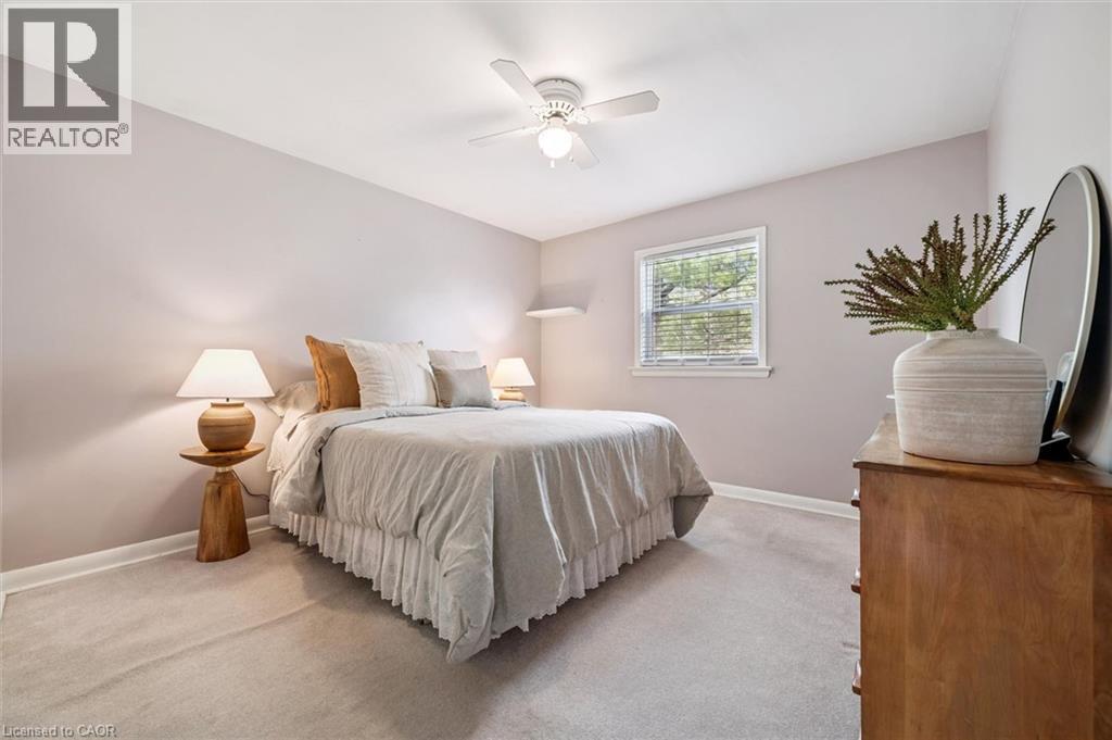 This room features light-colored walls and carpeting, a window with horizontal blinds, and a ceiling fan - 155 Hungerford Road, Cambridge, ON - Indoor Photo Showing Bedroom
