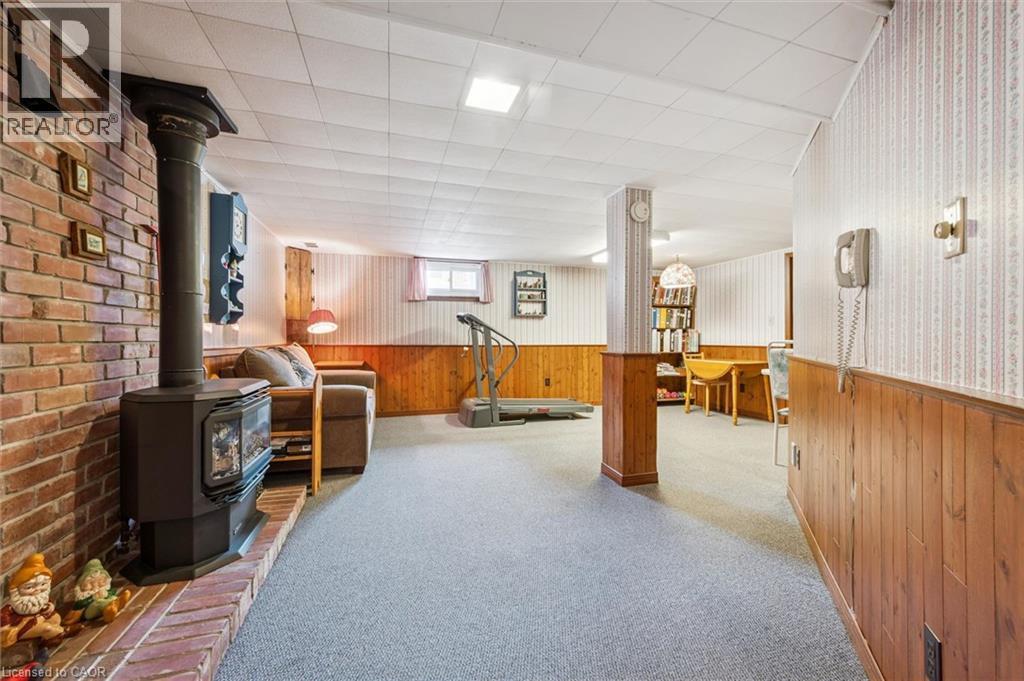 This versatile space features a brick accent wall with a stove, carpeted flooring, and a drop ceiling - 155 Hungerford Road, Cambridge, ON - Indoor Photo Showing Other Room
