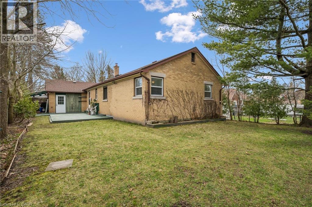 The property features a spacious lawn, a rear deck, and mature trees providing shade - 155 Hungerford Road, Cambridge, ON - Outdoor
