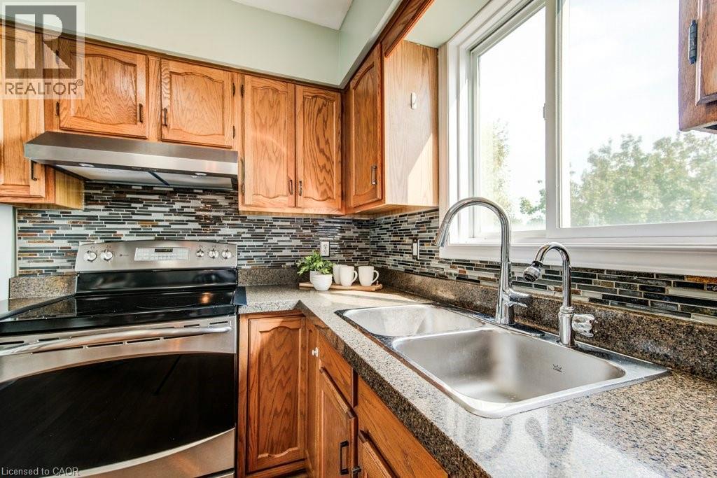 Kitchen with stainless steel electric stove and wood finish cabinetry - 633 Grange Crescent, Waterloo, ON - Indoor Photo Showing Kitchen With Double Sink