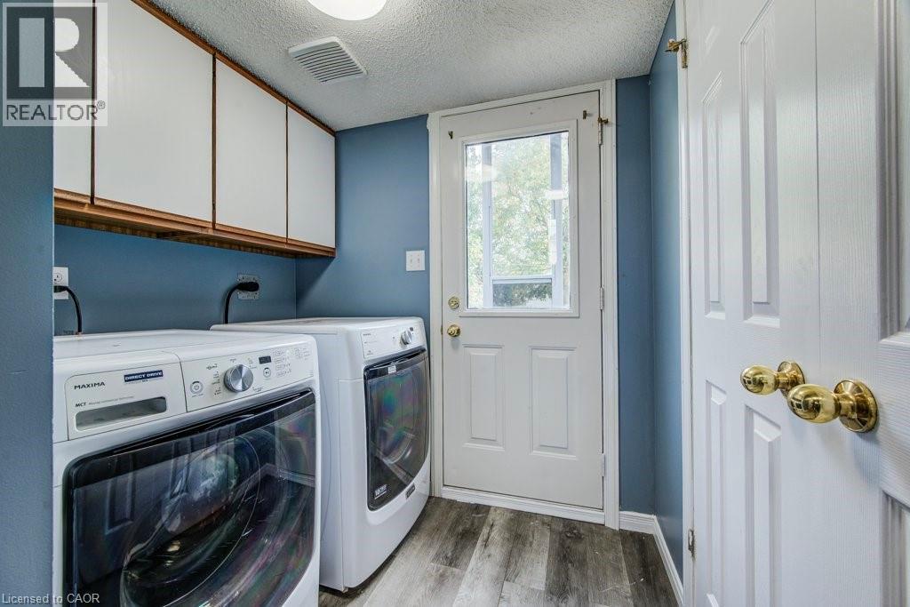 Laundry area with a textured ceiling, independent washer and dryer, light wood finished floors, and cabinet space - 633 Grange Crescent, Waterloo, ON - Indoor Photo Showing Laundry Room