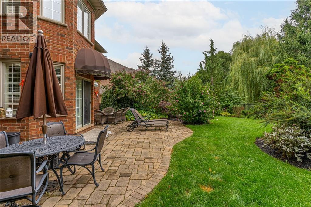 The property features a brick exterior, a paved patio area, and a lush green lawn - 4278 Clubview Drive, Burlington, ON - Outdoor With Deck Patio Veranda
