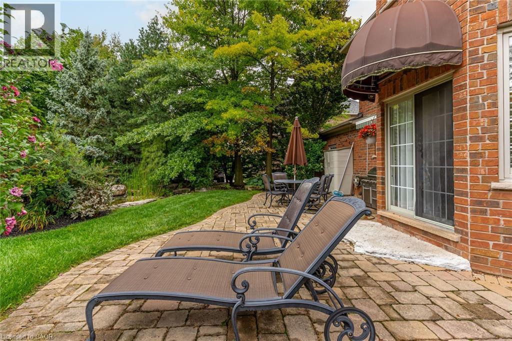 The property features a brick exterior with a sliding glass door leading to a paver patio - 4278 Clubview Drive, Burlington, ON - Outdoor With Deck Patio Veranda
