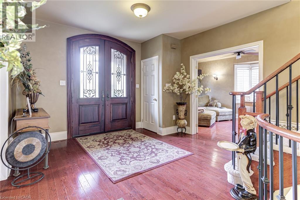 The property features an inviting entryway with rich wood flooring and an arched double front door with decorative glass inserts - 4278 Clubview Drive, Burlington, ON - Indoor Photo Showing Other Room
