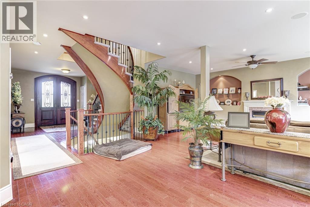The property features a grand entryway with a double wooden door and an elegant curved staircase with wrought iron balusters - 4278 Clubview Drive, Burlington, ON - Indoor Photo Showing Other Room