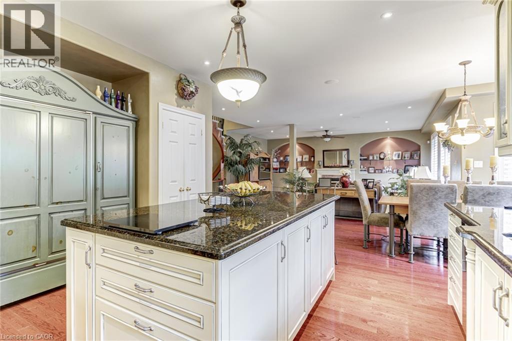 The kitchen features a large island with a dark granite countertop, light-colored cabinetry, and hardwood flooring - 4278 Clubview Drive, Burlington, ON - Indoor Photo Showing Kitchen With Upgraded Kitchen