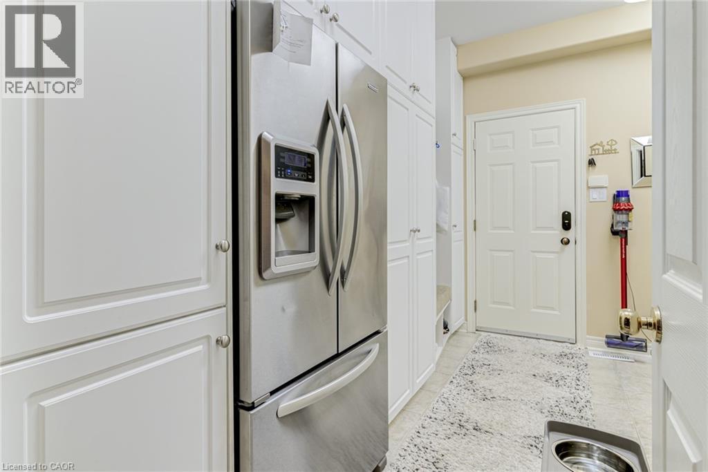 This space features white cabinetry and a stainless steel refrigerator with a water and ice dispenser - 4278 Clubview Drive, Burlington, ON - Indoor Photo Showing Other Room
