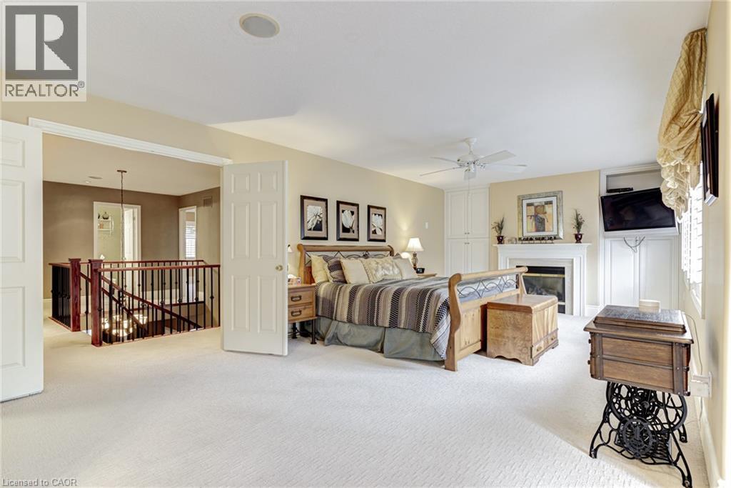 Spacious room featuring light-colored carpet flooring, a fireplace with a white mantel, and built-in white cabinetry - 4278 Clubview Drive, Burlington, ON - Indoor Photo Showing Bedroom With Fireplace