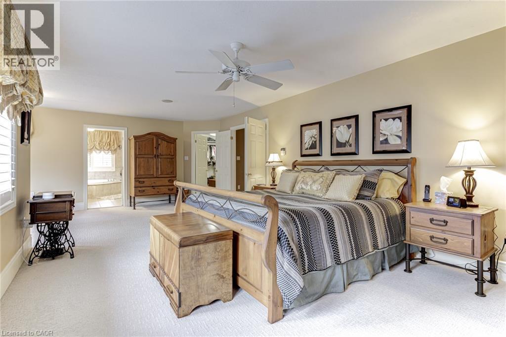 The bedroom features neutral-toned carpeting, a ceiling fan, and framed wall art - 4278 Clubview Drive, Burlington, ON - Indoor Photo Showing Bedroom