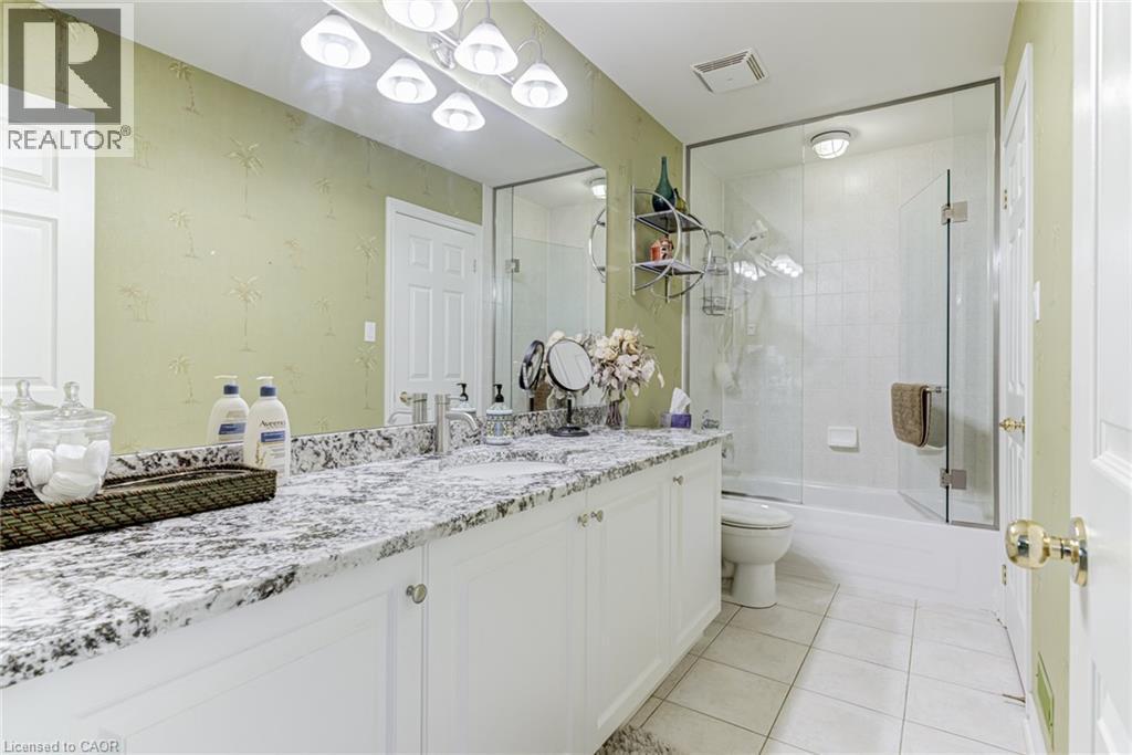 Bathroom featuring a double vanity with a speckled countertop, a large mirror, and a glass-enclosed shower - 4278 Clubview Drive, Burlington, ON - Indoor Photo Showing Bathroom
