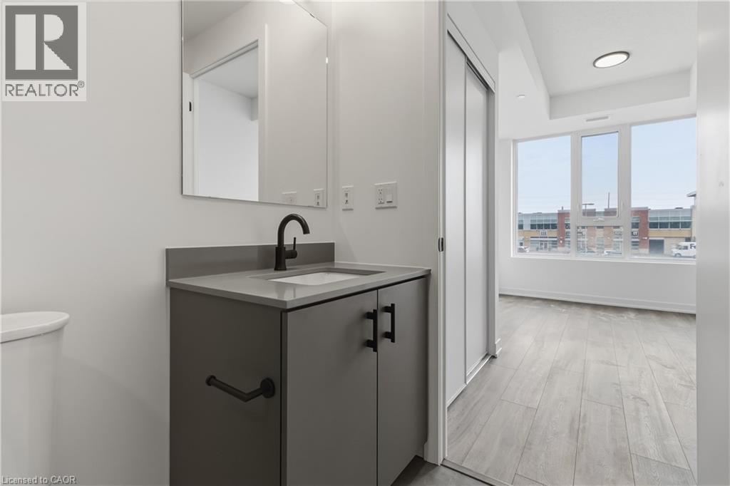 The property features a modern bathroom vanity with a basin sink and a dark faucet, alongside a sleek mirror - 4878 Powers Common Unit# 224, Burlington, ON - Indoor Photo Showing Bathroom