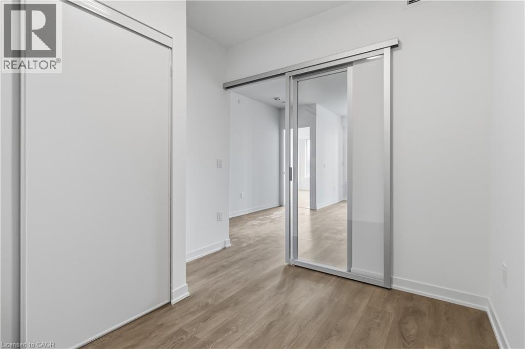 Interior space featuring light wood-style flooring, white walls, and a sliding glass door with a frosted panel - 4878 Powers Common Unit# 224, Burlington, ON - Indoor Photo Showing Other Room