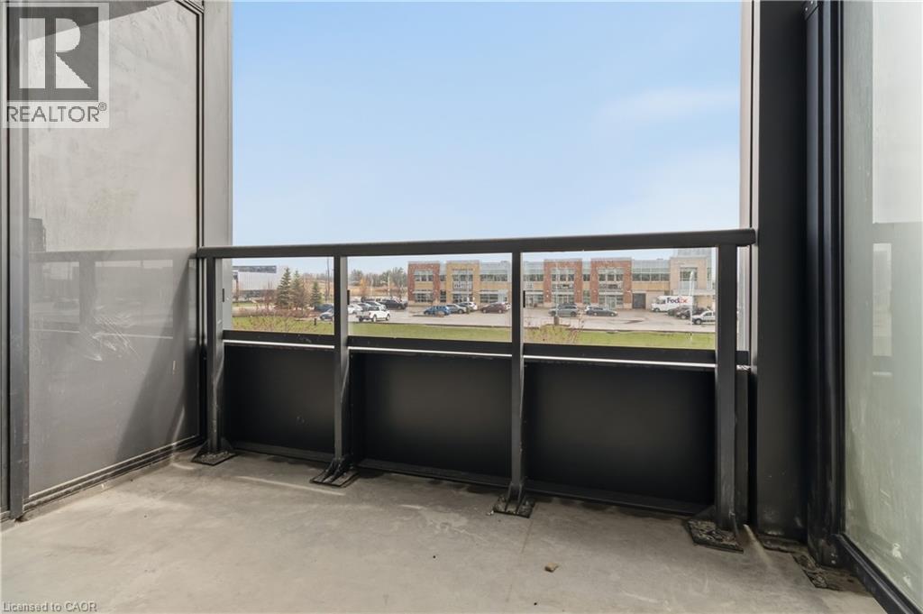 The property includes a balcony featuring a glass and metal railing, a concrete floor, and views of a commercial area - 4878 Powers Common Unit# 224, Burlington, ON - Outdoor With Balcony With Exterior